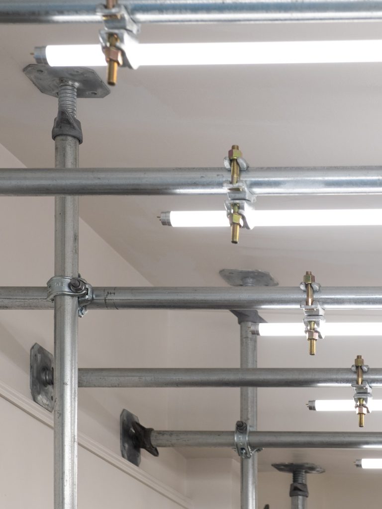 Close-up of galvanized steel scaffolding with mounted neon led lights, showcasing an industrial aesthetic blending function and minimalism.