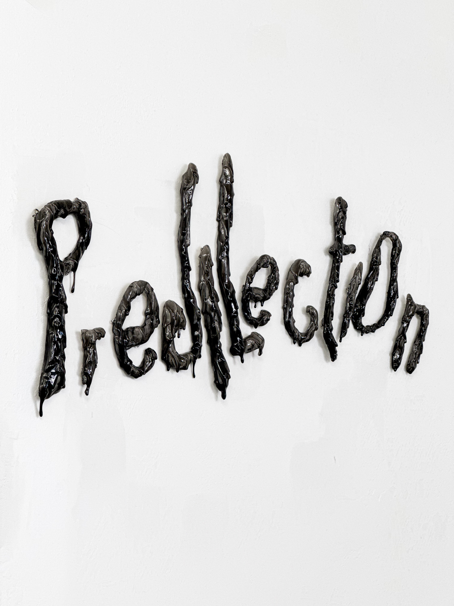Handmade black sculpture by Fabien Ficher spelling 'Predilection' with a textured, dripping effect, enhancing the boutique's artistic vibe.