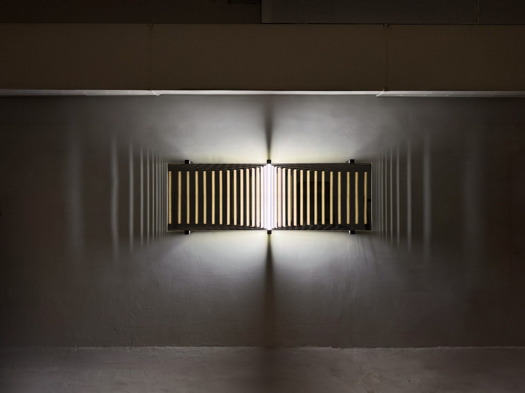 Light art from FABIEN FICHER, revealing the mirrored glass structure with luminous reflections repeating into depth and shadow effect against the wall.